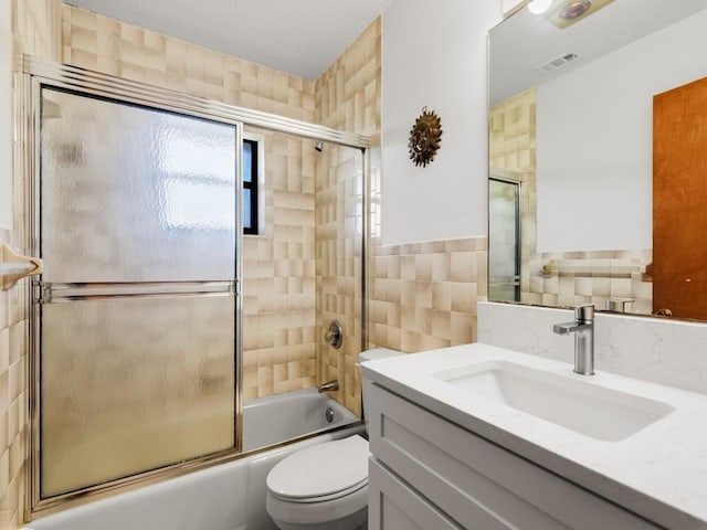 1626 4th Ct, Vero Beach, FL 32960 - bathroom featuring tile walls, vanity, toilet, and combined bath / shower with glass door