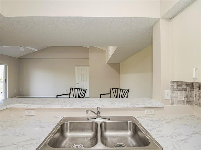 kitchen featuring a textured ceiling, sink, and lofted ceiling