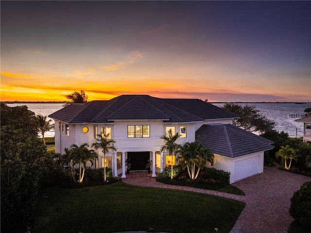 view of front of home featuring a yard, a garage, and a water view