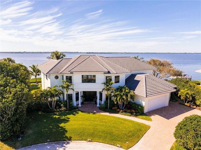 view of front facade with a front yard, a garage, a water view, and a balcony