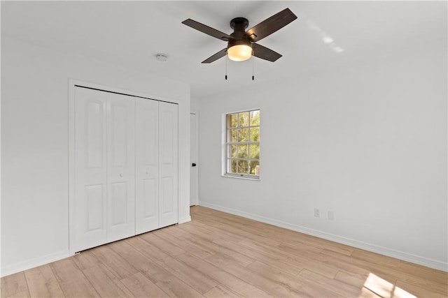 unfurnished bedroom featuring a ceiling fan, a closet, baseboards, and light wood finished floors