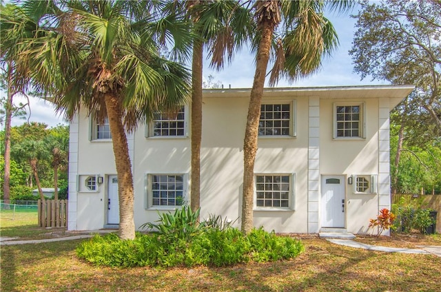 view of front of home with a front yard, fence, and stucco siding