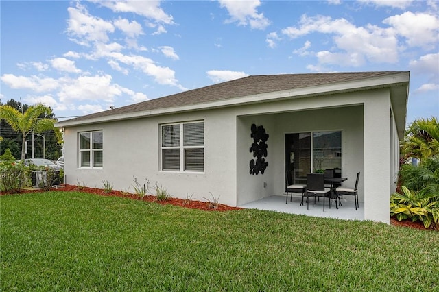 back of property with a patio area, stucco siding, a shingled roof, and a yard