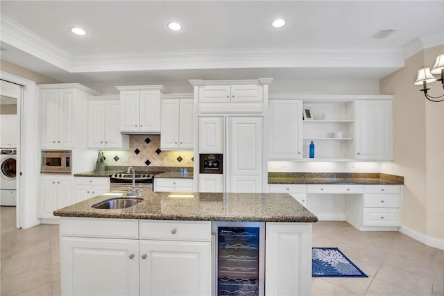 kitchen with beverage cooler, a center island with sink, built in study area, built in appliances, and open shelves