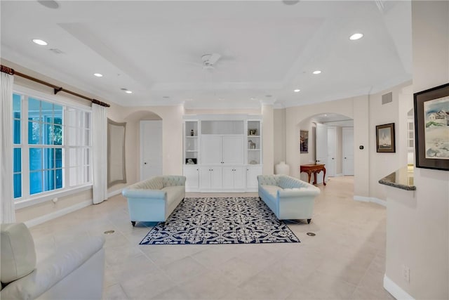 living area featuring arched walkways, a raised ceiling, visible vents, and recessed lighting