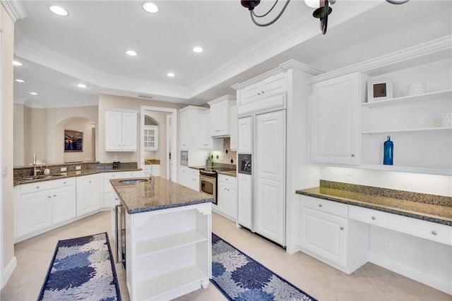 kitchen featuring open shelves, paneled built in fridge, a sink, and stainless steel range with electric cooktop