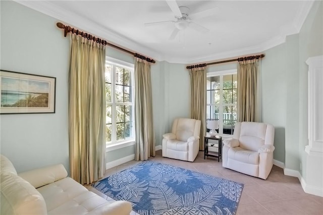 living area with light tile patterned flooring, crown molding, baseboards, and ceiling fan