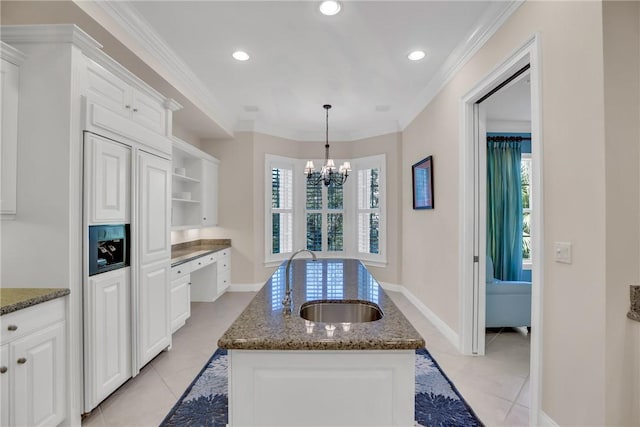 kitchen featuring a center island with sink, a healthy amount of sunlight, a sink, and dark stone countertops