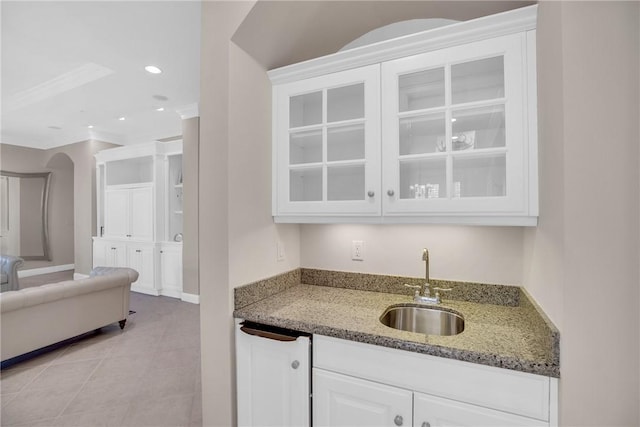 kitchen featuring glass insert cabinets, white cabinetry, light stone counters, and a sink