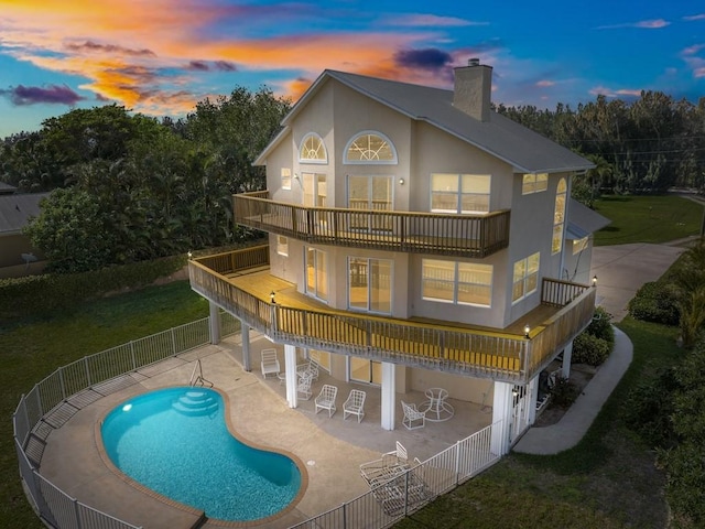 8820 44th Ave, Sebastian, FL 32958 - back of house at dusk featuring a balcony, a chimney, a fenced backyard, a patio area, and stucco siding
