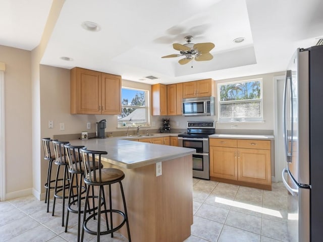 8820 44th Ave, Sebastian, FL 32958 - kitchen featuring appliances with stainless steel finishes, a peninsula, a tray ceiling, light tile patterned floors, and a breakfast bar