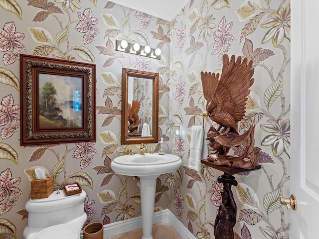 half bath with toilet, baseboards, and wallpapered walls