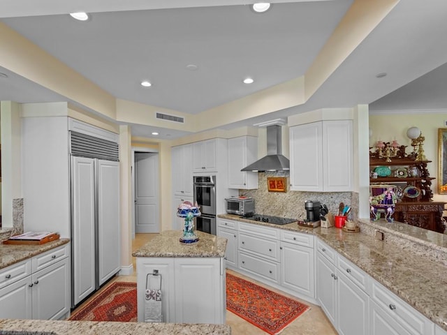 kitchen with wall chimney exhaust hood, white cabinets, visible vents, paneled built in fridge, and stainless steel double oven