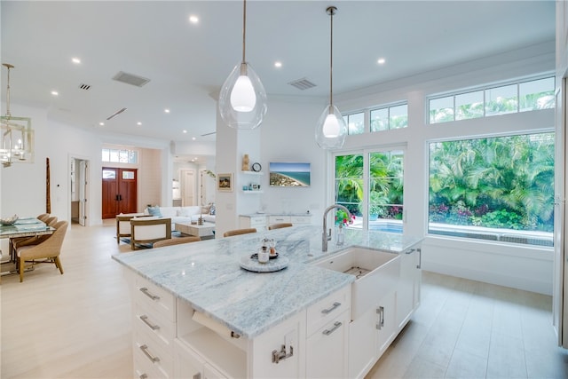 kitchen with a wealth of natural light, an island with sink, and hanging light fixtures