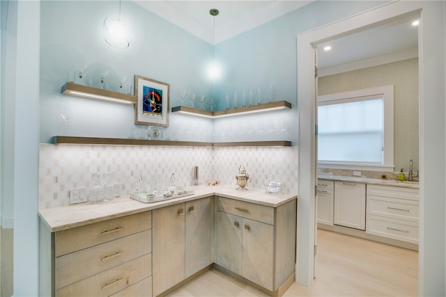 kitchen featuring light wood-type flooring, hanging light fixtures, tasteful backsplash, and light stone countertops