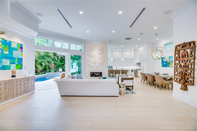 living room featuring a chandelier, light hardwood / wood-style floors, and a large fireplace