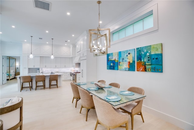 dining area featuring sink, an inviting chandelier, and light hardwood / wood-style flooring