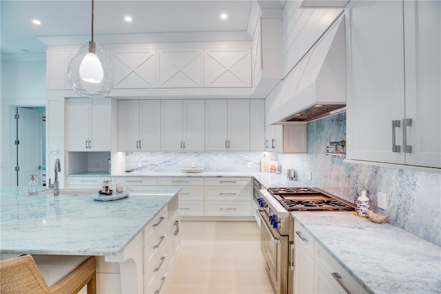 kitchen featuring white cabinetry, light stone counters, a breakfast bar area, stainless steel stove, and pendant lighting