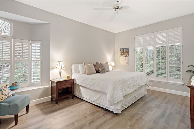 bedroom featuring ceiling fan, multiple windows, and light wood-type flooring