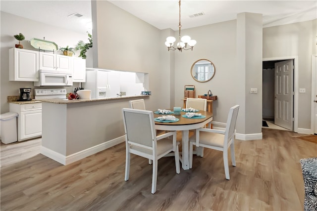 dining space with light wood-type flooring and a chandelier