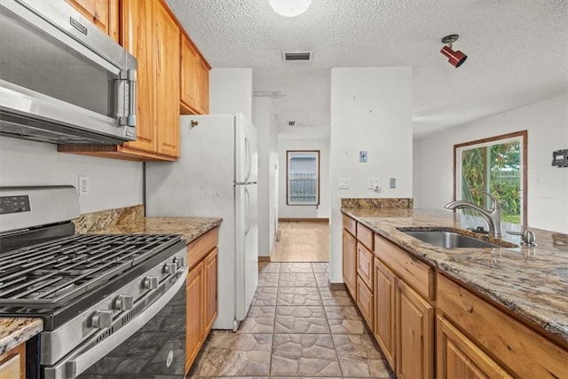 233 13th St SW, Vero Beach, FL 32962 - kitchen with appliances with stainless steel finishes, a sink, light stone countertops, a textured ceiling, and light stone finish floors