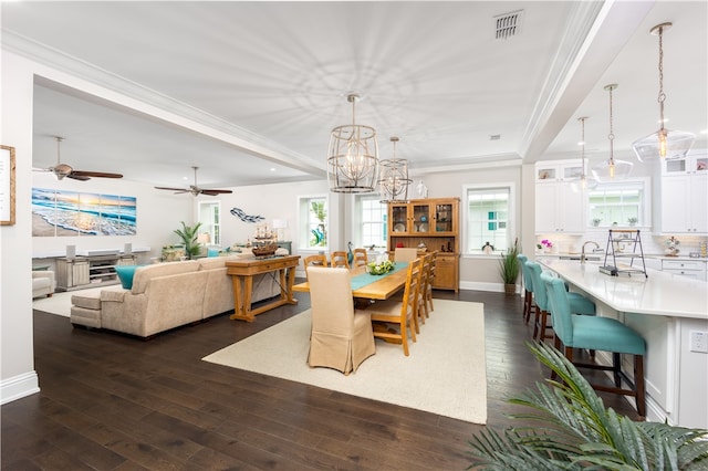 dining area with crown molding, sink, dark wood-type flooring, and ceiling fan with notable chandelier