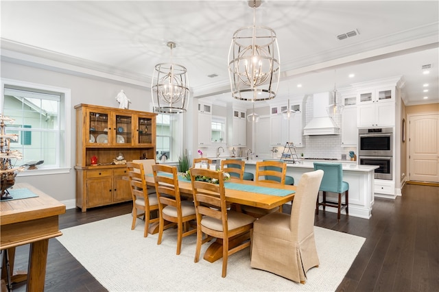 dining area with sink, ornamental molding, dark wood-type flooring, and a notable chandelier