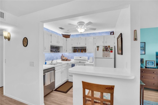 kitchen featuring light wood finished floors, light countertops, visible vents, white appliances, and a peninsula