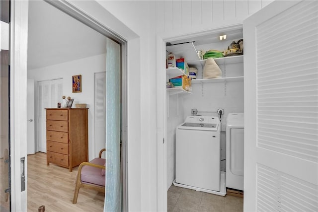 clothes washing area with laundry area, separate washer and dryer, and light wood-style flooring