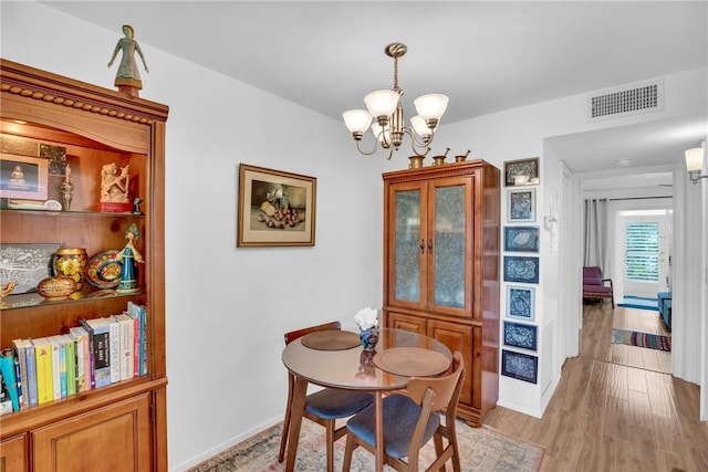 dining space with baseboards, an inviting chandelier, visible vents, and light wood-style floors