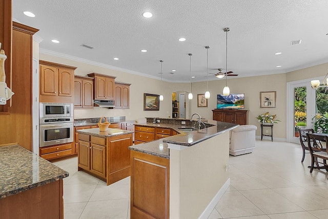 kitchen featuring a center island with sink, hanging light fixtures, a textured ceiling, sink, and appliances with stainless steel finishes