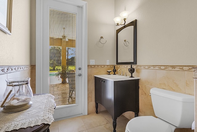 bathroom featuring toilet, vanity, tile walls, and tile patterned floors