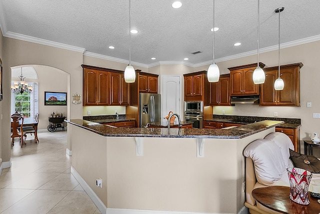 kitchen featuring a kitchen breakfast bar, appliances with stainless steel finishes, a large island with sink, and decorative light fixtures