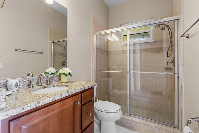 bathroom with vanity, toilet, and a shower with shower door