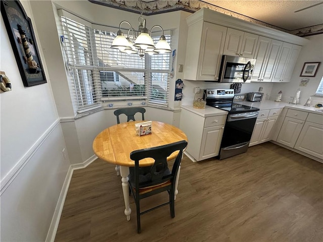 kitchen with a chandelier, stainless steel appliances, and white cabinetry