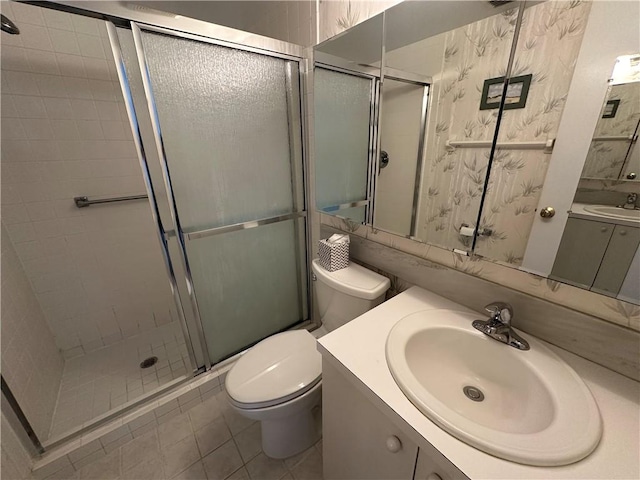 bathroom with tile patterned floors, vanity, toilet, and a shower with door