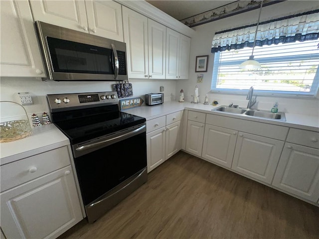 kitchen with dark hardwood / wood-style flooring, stainless steel appliances, sink, white cabinetry, and hanging light fixtures