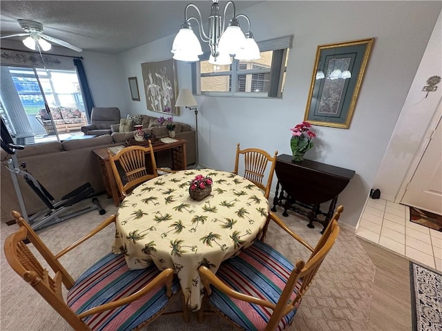 dining space featuring ceiling fan with notable chandelier, wood-type flooring, and a textured ceiling