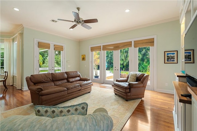 living room with ornamental molding, a wealth of natural light, light hardwood / wood-style floors, and french doors