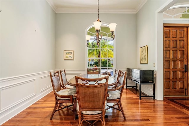 dining room featuring ornamental molding, wood-type flooring, and a notable chandelier