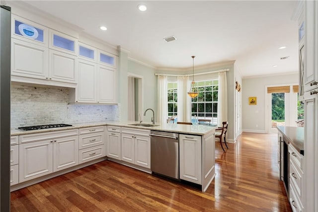 kitchen with sink, stainless steel appliances, ornamental molding, white cabinets, and decorative light fixtures