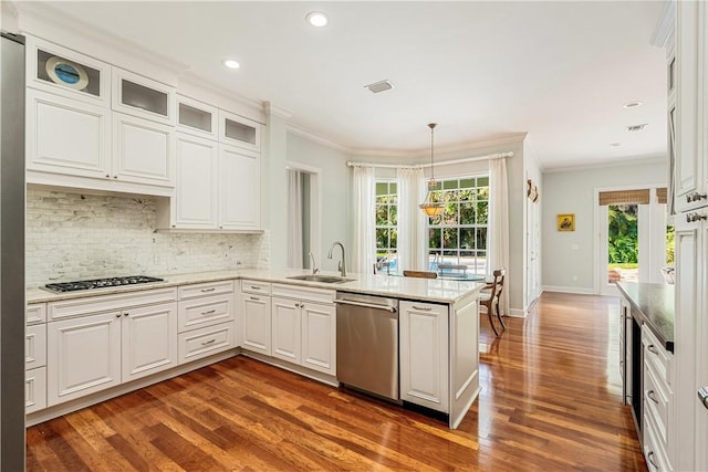 kitchen with sink, appliances with stainless steel finishes, hanging light fixtures, white cabinets, and kitchen peninsula