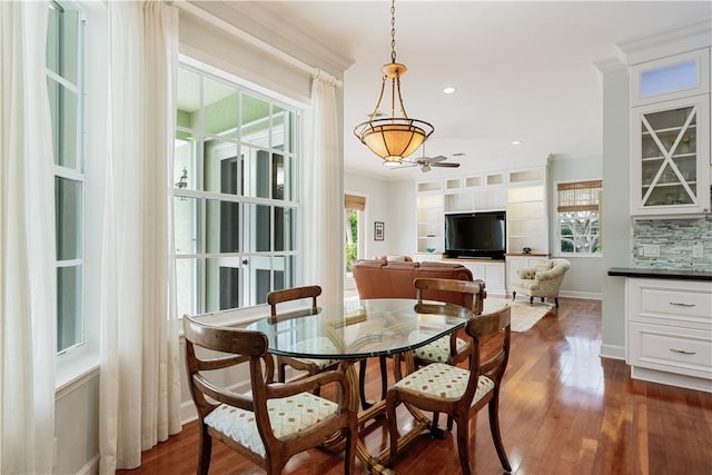 dining area with ornamental molding, dark wood-type flooring, and a wealth of natural light