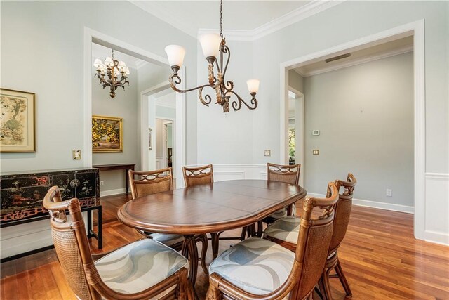 dining space featuring crown molding, hardwood / wood-style flooring, and a notable chandelier