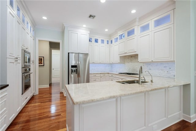 kitchen with stainless steel appliances, white cabinets, light stone counters, and kitchen peninsula