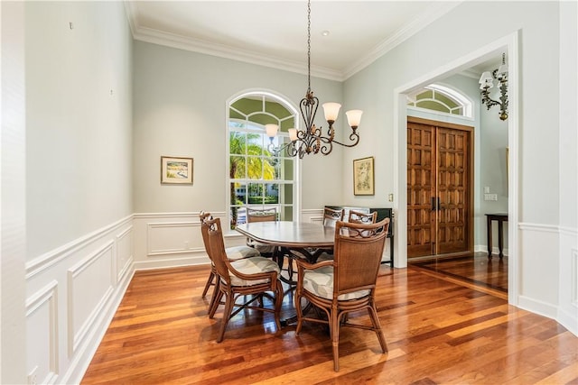 dining area with hardwood / wood-style flooring, crown molding, and a chandelier