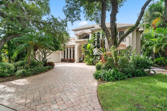 mediterranean / spanish-style home featuring a garage and a front lawn