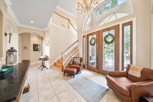 foyer with a towering ceiling, french doors, light tile patterned floors, and crown molding