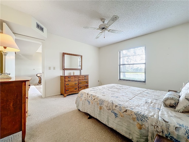 bedroom with ceiling fan, a textured ceiling, and light carpet