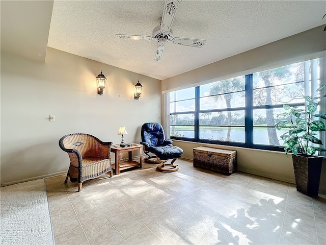 sitting room featuring a textured ceiling, a water view, and ceiling fan